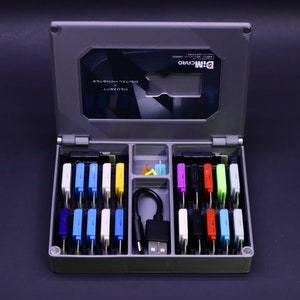 May include: A gray plastic case with a clear lid, containing a variety of colorful memory cards and a USB cable. The lid has the text "DIMM CARD" printed on it.