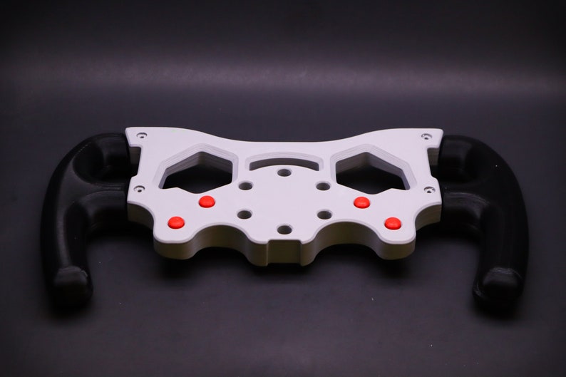 May include: White plastic steering wheel frame with black grips and red buttons.