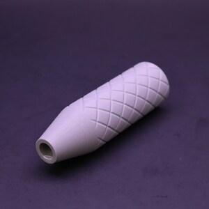 May include: A light grey, cylindrical object featuring a diamond pattern carved into its surface. The object narrows to a smaller opening at one end. It appears to be a handle or grip for a tool or device.