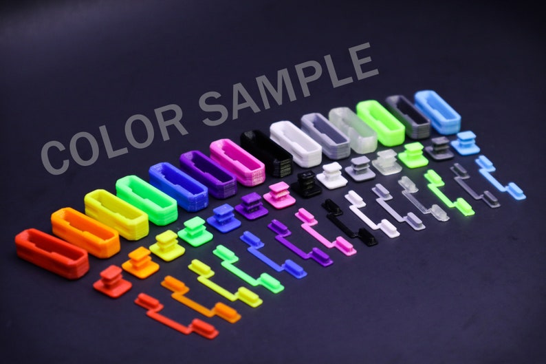May include: A collection of colorful plastic components, including rectangular frames, square buttons, and elongated levers, arranged on a dark surface. The components are in various colors such as red, orange, yellow, green, blue, purple, black, and white. The text "COLOR SAMPLE" is visible.