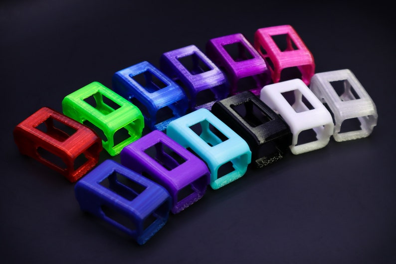 Pode incluir: Um conjunto de 12 capas coloridas impressas em 3D para um rastreador de fitness. As capas est&atilde;o dispostas em uma linha, com cores que variam do vermelho ao roxo.