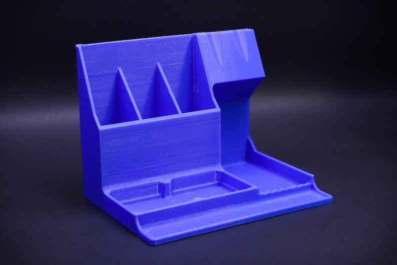 May include: A blue plastic desk organizer with multiple compartments for pens, pencils, and other office supplies. It has a raised section for a phone or other device.
