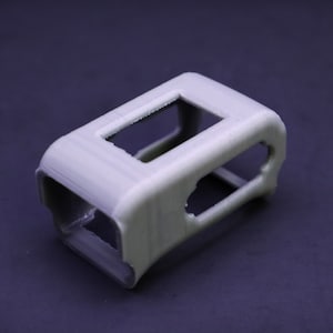 May include: A gray 3D printed case with multiple openings. The case is designed to hold a small electronic device.