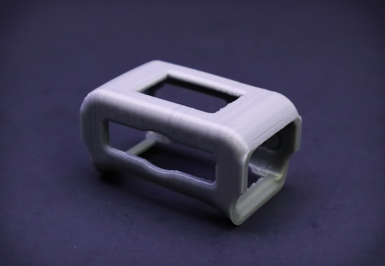 May include: A gray plastic 3D printed case with a rectangular opening.