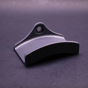 May include: A black metal wall mount with a curved shape and a hole for hanging.
