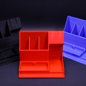 May include: Three desktop organizers in black, red, and blue. Each organizer has multiple compartments for pens, pencils, and other office supplies.