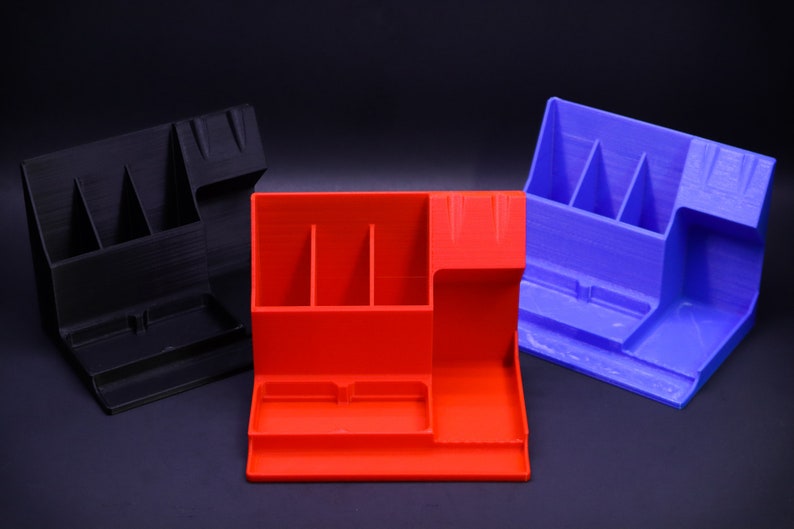 May include: Three desktop organizers in black, red, and blue. Each organizer has multiple compartments for pens, pencils, and other office supplies.
