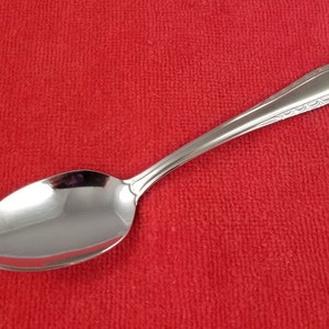 May include: A silver spoon with a decorative handle. The spoon has a rounded bowl and a long, slender handle.