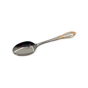 May include: A stainless steel spoon with a gold-colored decorative handle. The spoon has a polished, reflective surface and a teardrop-shaped bowl. The handle features a gold-colored floral design. The spoon is designed for serving.