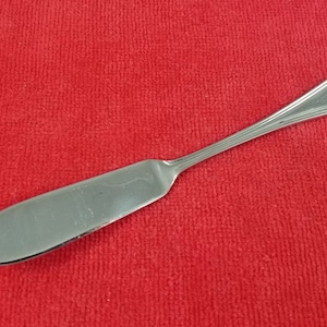 May include: A silver butter knife with a rounded handle and a slightly curved blade.