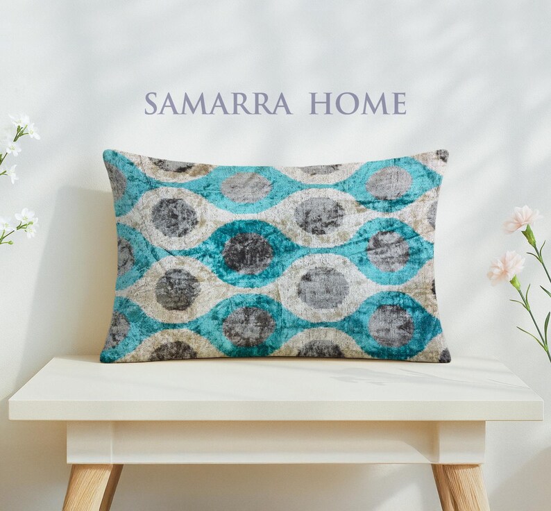 May include: Rectangular decorative pillow with a teal, gray, and cream geometric pattern. The pillow is on a white table. The text "SAMARRA HOME" is above the pillow.