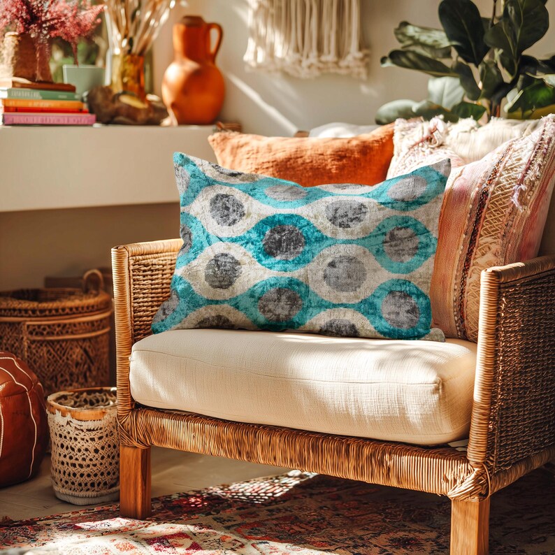 May include: A wicker armchair with a cream-colored cushion holds a decorative pillow with a teal, gray, and white circular pattern. Other pillows in shades of orange and pink are visible. The room is decorated with baskets, plants, and a rug.