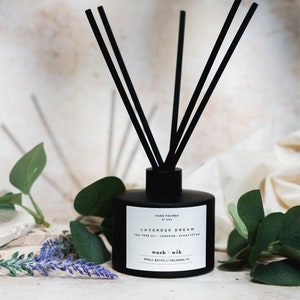 May include: Black diffuser bottle with black reeds and a white label that reads "HAND POURED", "LAVENDER DREAM", "TEA TREE OIL - CAMPHOR - EUCALYPTUS", "wash + wik", "SMALL BATCH // ORLANDO, FL".