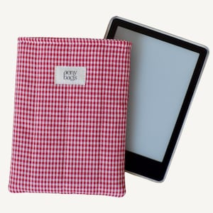 May include: Red and white gingham e-reader case with the text "aery bags" on a white label. The case is shown with an e-reader inside.