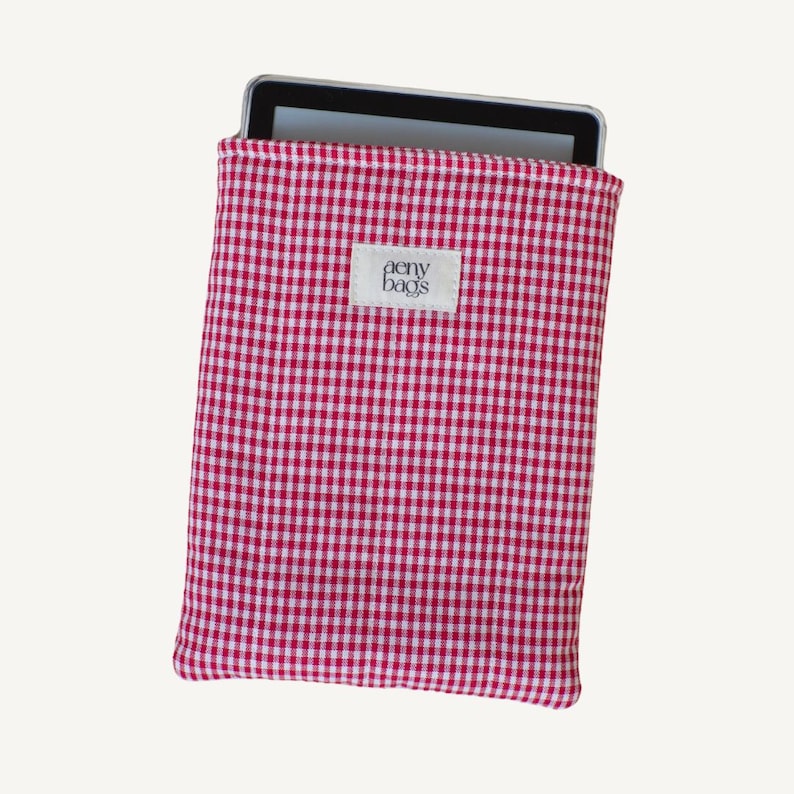 May include: Red and white gingham fabric tablet sleeve with the text "aery bags" on a white tag.
