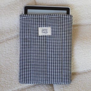 May include: Black and white gingham fabric tablet sleeve with the text "aeny bags" on a white label.