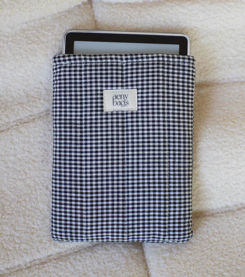 May include: Black and white gingham fabric tablet sleeve with the text "aeny bags" on a white label.