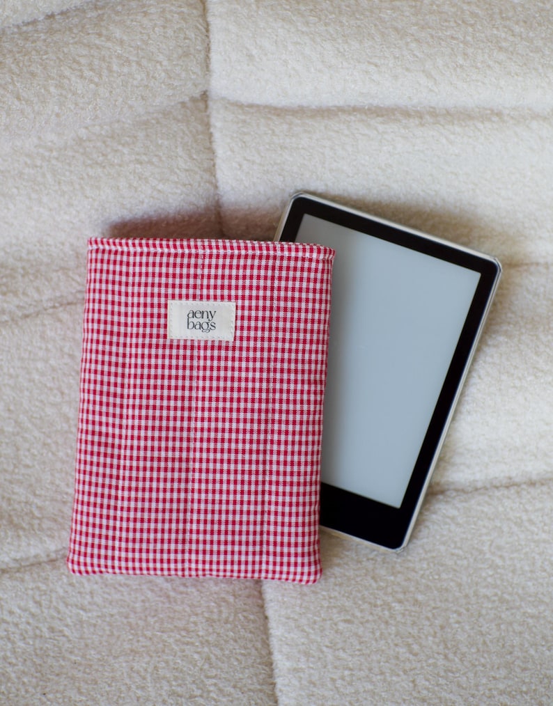 May include: Red and white gingham fabric e-reader case with a small white label that says "aery bags".