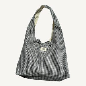 May include: A black and white gingham tote bag with a white label that says "perry bags".