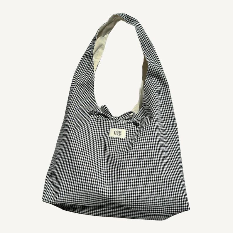 May include: A black and white gingham tote bag with a white label that says "perry bags".