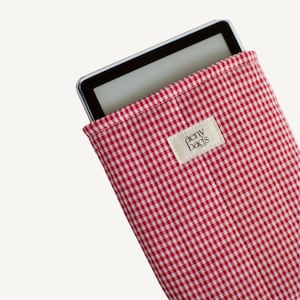 May include: Red and white gingham fabric e-reader case with a white label that says "aemy bags".