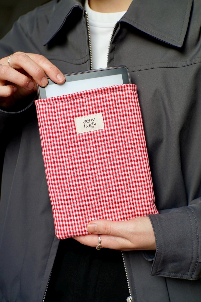 May include: Red and white gingham fabric tablet case with the text "aeny bags" on a white label.