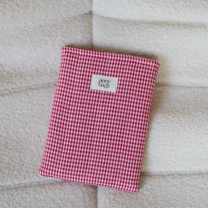 May include: Red and white gingham fabric pouch with a white label that says "aery bags".