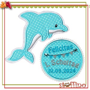 Könnte beinhalten: Ein blauer und weißer gepunkteter Delfin mit weißem Umriss und einem blauen und weißen gepunkteten Kreis mit dem Text "Felicitas 1. Schultag 10.09.2024" in Silber.