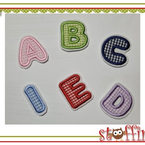 Könnte beinhalten: Sechs Filzbuchstaben in verschiedenen Farben und Mustern, darunter rosa, rot, grün, blau und lila. Die Buchstaben ergeben das Wort "ABCIED".