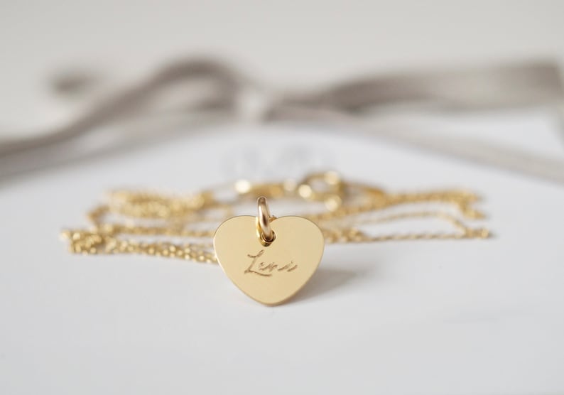 May include: A gold heart-shaped pendant necklace with the name "Lisa" engraved on it.