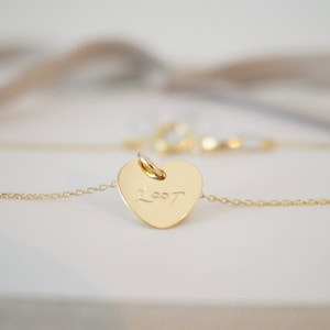 May include: A gold heart-shaped pendant necklace with the word "Lost" inscribed on it.