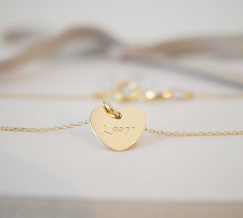 May include: A gold heart-shaped pendant necklace with the word "Lost" inscribed on it.