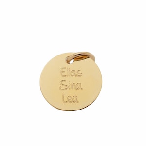Op de afbeelding: Een ronde gouden tag met de namen Elias, Sina en Lea erop gegraveerd.