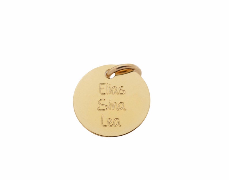 Op de afbeelding: Een ronde gouden tag met de namen Elias, Sina en Lea erop gegraveerd.