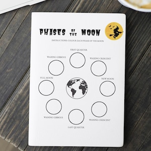 Peut inclure: Une feuille de papier blanche avec le texte "PHASES OF THE MOON" et des instructions pour colorier chaque phase. Les phases sont représentées par des cercles autour d'une carte du monde. Une sorcière sur un balai est dans le coin supérieur droit.