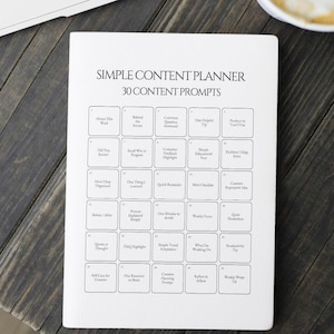 May include: A white Simple Content Planner with 30 content prompts, including "About This Week" and "Did You Know?" The planner is on a dark wooden surface, with a coffee cup and a laptop visible in the background.