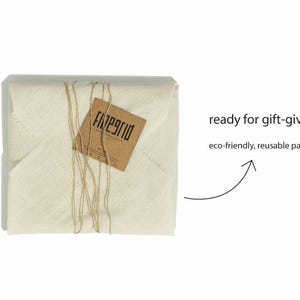 May include: A wrapped package in off-white fabric tied with twine, featuring a brown tag with the text "finegrid". The image includes the text "ready for gift-giving!" and "eco-friendly, reusable packaging".