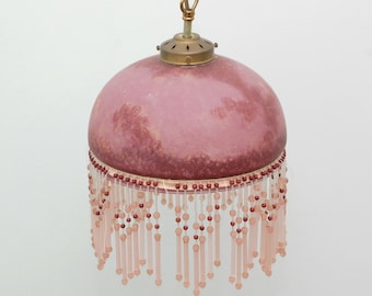 May include: A pink glass pendant light with a beaded fringe. The glass shade has a marbled effect and the beads are pink and red.