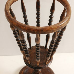 May include: A wooden plant stand with a round top and a base. The stand has a decorative design of small beads around the spindles.