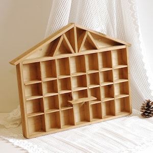 Peut inclure: Une étagère de présentation en bois avec un design en forme de maison et de multiples compartiments. L'étagère est en bois brun clair et a un aspect rustique.