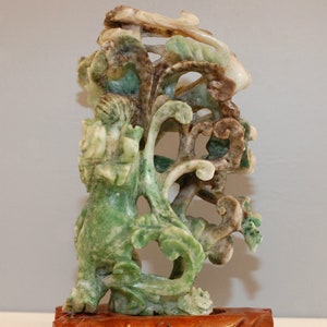 Peut inclure: Une sculpture en jade vert, brun et blanc d'un arbre stylisé avec des sculptures complexes. La sculpture est montée sur une base en bois.