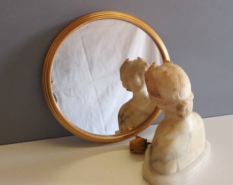 Peut inclure: Un miroir rond avec un cadre doré et un buste de femme en marbre blanc qui s'y reflète.
