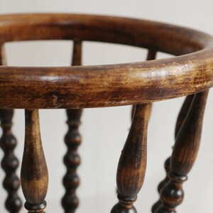 May include: A wooden basket with a round top and beaded legs. The basket is made of dark brown wood and has a rustic appearance.