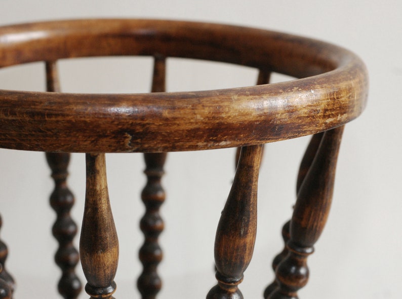 May include: A wooden basket with a round top and beaded legs. The basket is made of dark brown wood and has a rustic appearance.