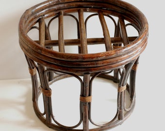 May include: A round, brown wicker ottoman with a woven top and a circular base. The ottoman is made of natural materials and has a rustic, vintage look.