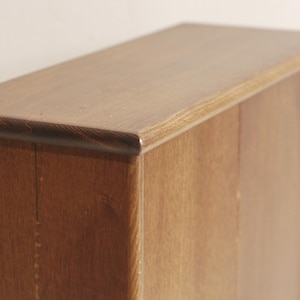 May include: A wooden cabinet with two doors. The cabinet is made of a dark wood with a natural finish. The doors are closed and have a simple design.