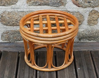 May include: A round, woven rattan stool with a lattice design on the top. The stool is made of natural brown rattan and has a simple, rustic style.