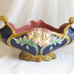 Pode incluir: Uma tigela grande de cerâmica adornada com duas alças. A tigela é decorada com um desenho floral em tons de azul, verde, rosa e dourado.