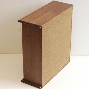 May include: A wooden cabinet with a brown finish and a light brown back panel. The cabinet has a simple design with no visible hardware.