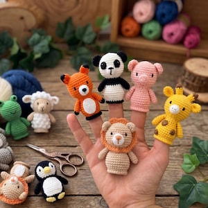 May include: A collection of small crocheted animal finger puppets including a fox, panda, pig, giraffe, lion, frog, sheep, rabbit, elephant, and penguin. The figures feature detailed stitching, embroidered facial features, and varied colours.